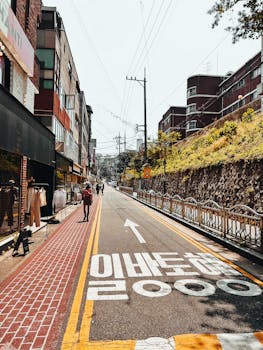 A picturesque urban street featuring shops, buildings, and an empty road under a clear sky.