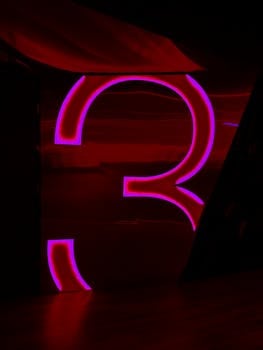 Vibrant neon number three on a dark background, perfect for cinematic themes.