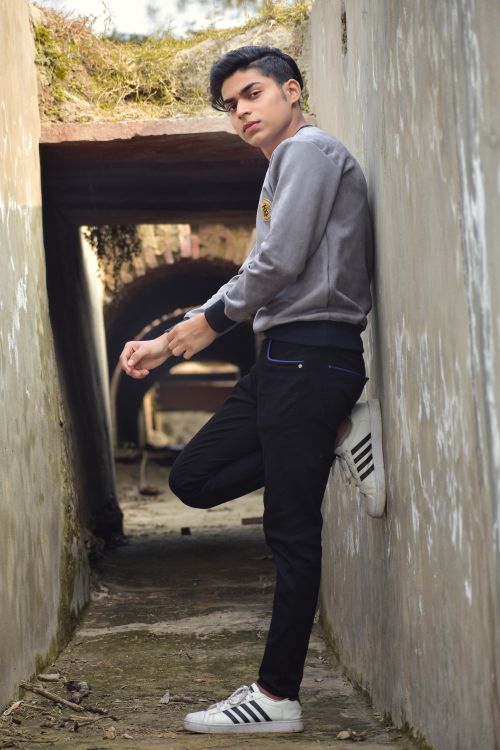 Free A fashionable young man posing in a narrow urban passage, showcasing casual style. Stock Photo