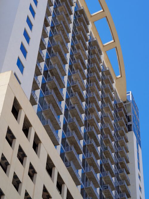 Free Low-angle shot showcasing modern skyscraper with geometric windows and balconies under clear sky. Stock Photo