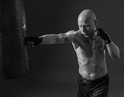 Free A Grayscale Photo of a Boxer Punching a Punching Bag Stock Photo