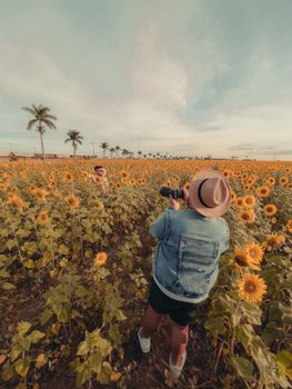 A photographer takes a picture in a vast sunflower field during summer.
