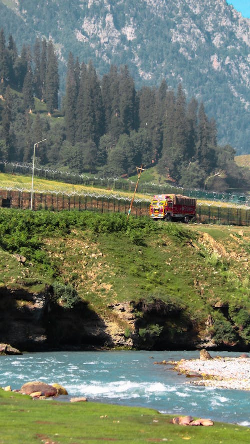 Red Train on Rail Near Green Grass Field and Mountain