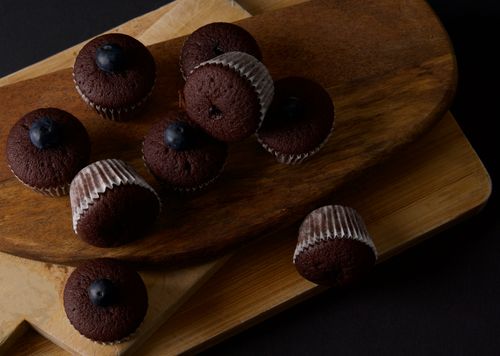 Free Homemade chocolate cupcakes topped with blueberries on a wooden board. Stock Photo