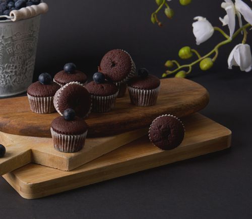 Free Indulge in mini chocolate muffins topped with blueberries, perfectly styled for a charming dessert presentation. Stock Photo