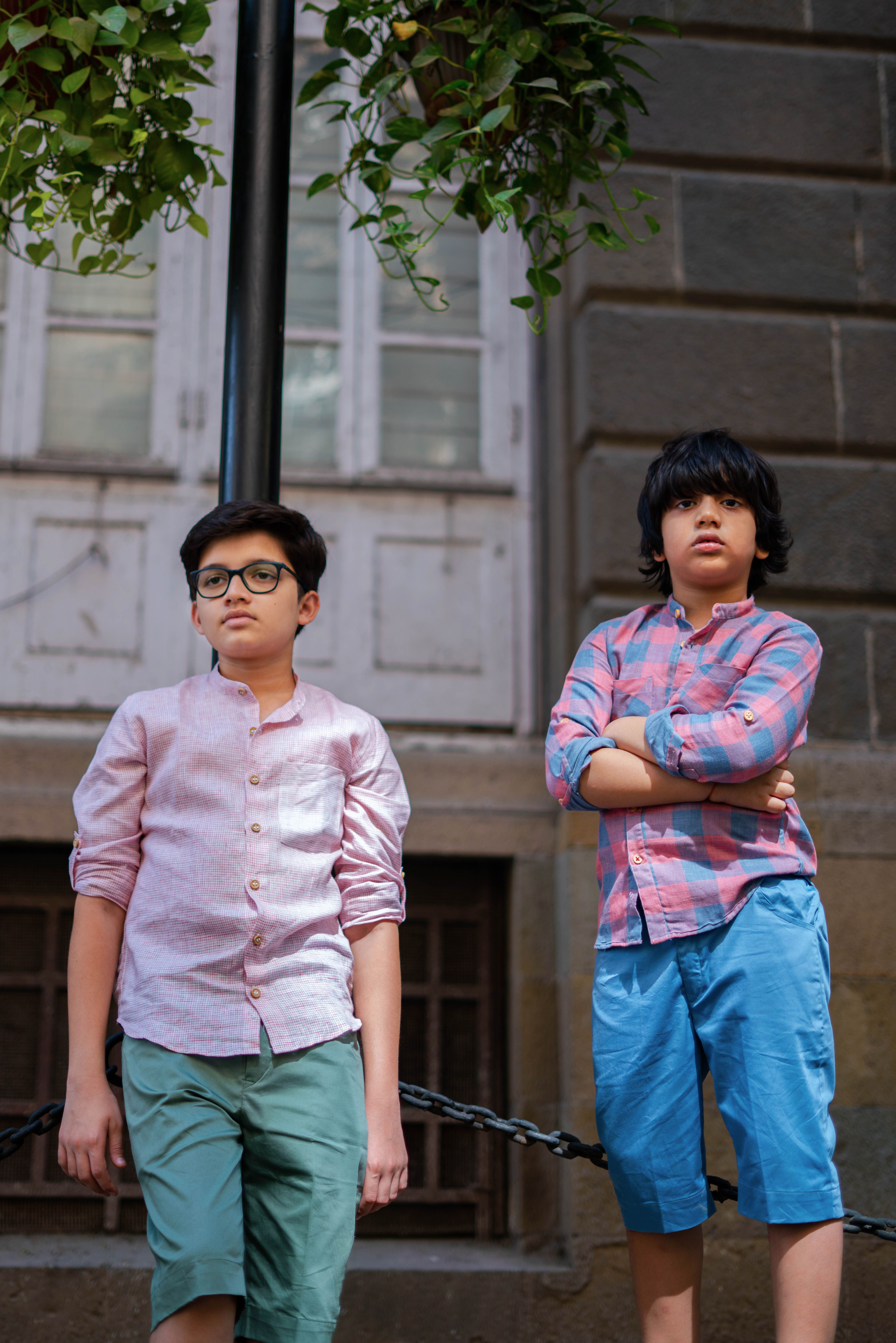 Street portrait of two boys in casual colorful attire standing outdoors.