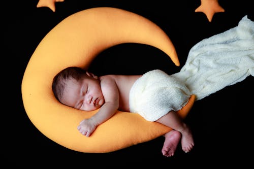 A Baby Sleeping on a Moon Stuffed Toy