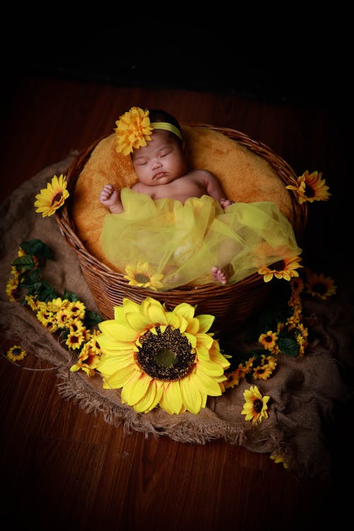 Free Baby in Yellow and White Floral Dress Lying on Brown and Green Floral Textile Stock Photo