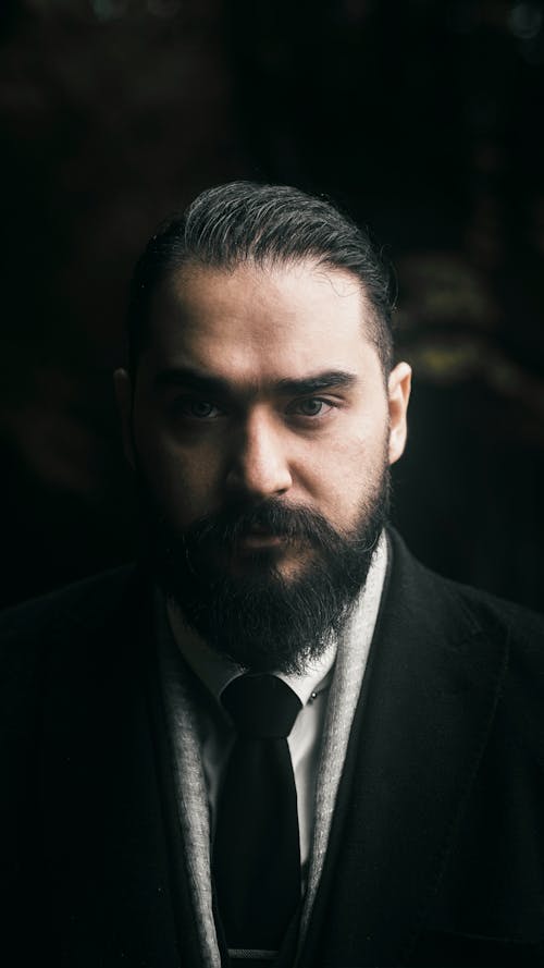A Bearded Man in Black Suit Looking with a Serious Face