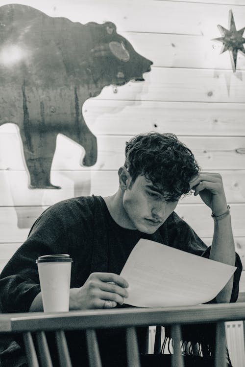 A Grayscale Photo of a Man Holding a Paper