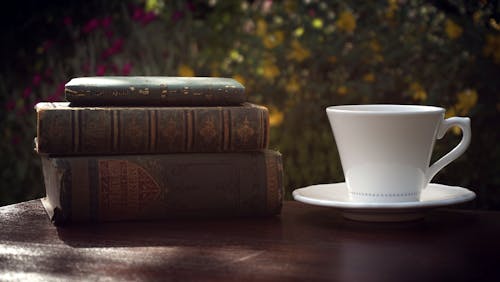 A Stack Of Old Books Next To Coffee Cup