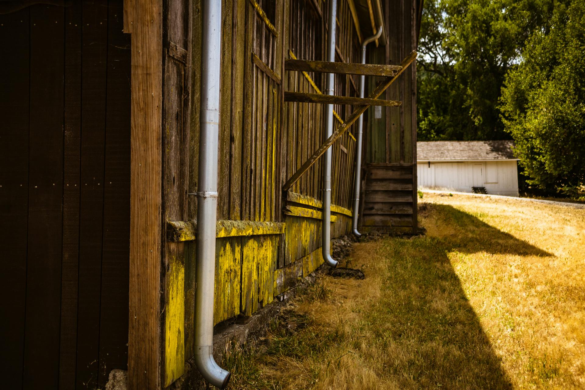 A rustic barn with rain gutters in a sunny rural setting, capturing rustic charm.