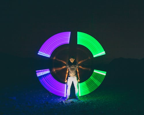Time Lapse Photography of Man Holding Purple and Green Light Fixtures