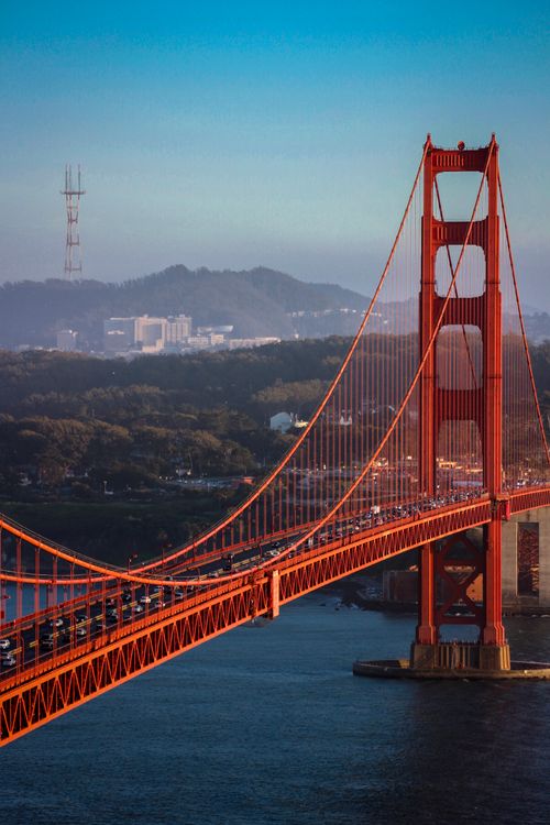 Free Aerial view of the iconic Golden Gate Bridge at sunset, showcasing its towering red structure over the bay. Stock Photo