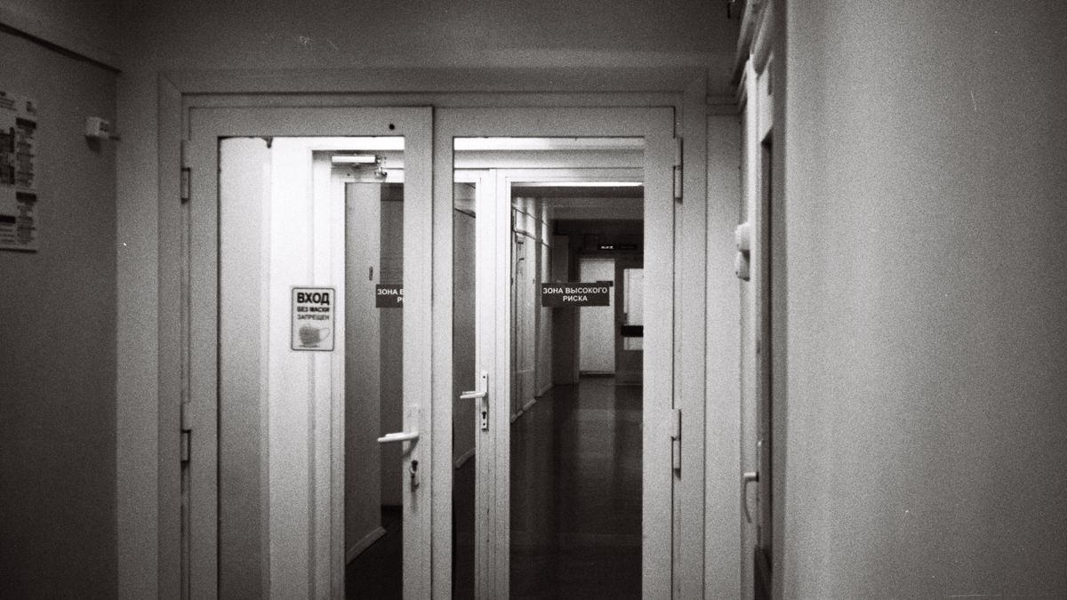 Empty hospital corridor in black and white, emphasizing open doors and healthcare environment.