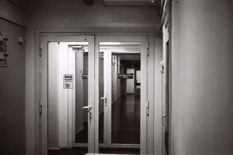 Empty hospital corridor in black and white, emphasizing open doors and healthcare environment.