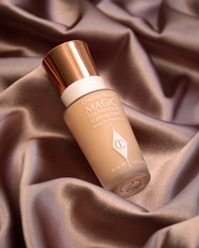 Elegant foundation bottle displayed on smooth silk, highlighting luxury skincare.