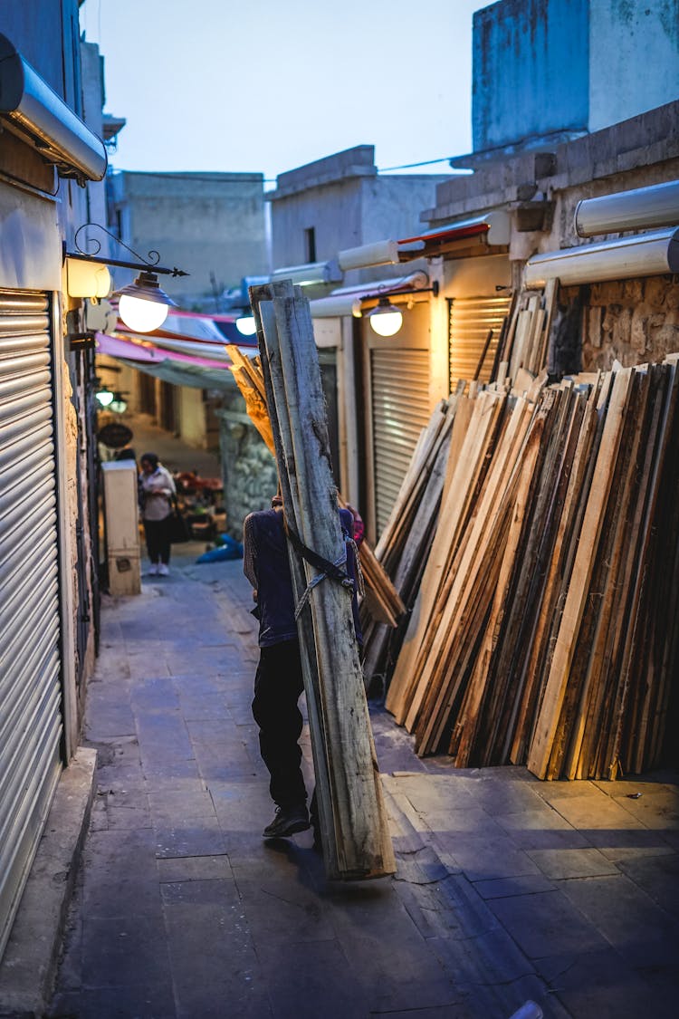 A Man Carrying A Package Of Lumber