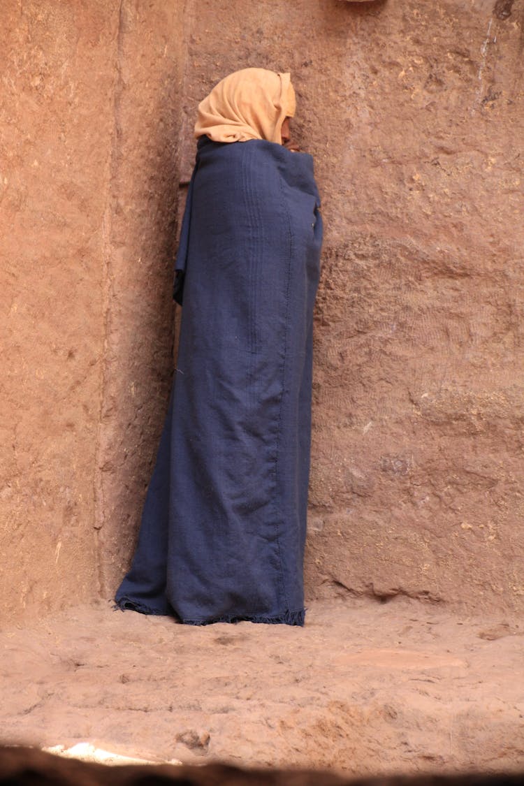 Person In A Turban Wrapped In A Gown, Standing By A Wall 