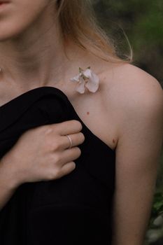 Close-up of a woman holding a black cloth, showcasing delicate flower and elegant ring.
