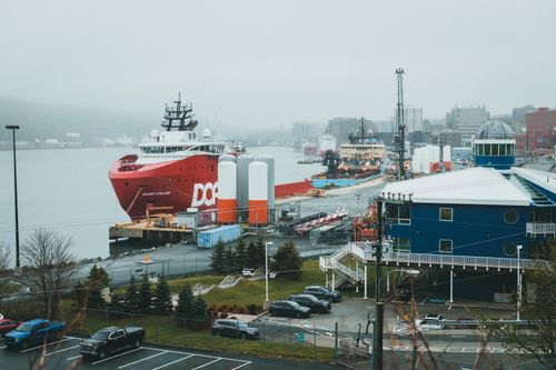 Free A vibrant port scene featuring large cargo ships docked near urban buildings. Stock Photo