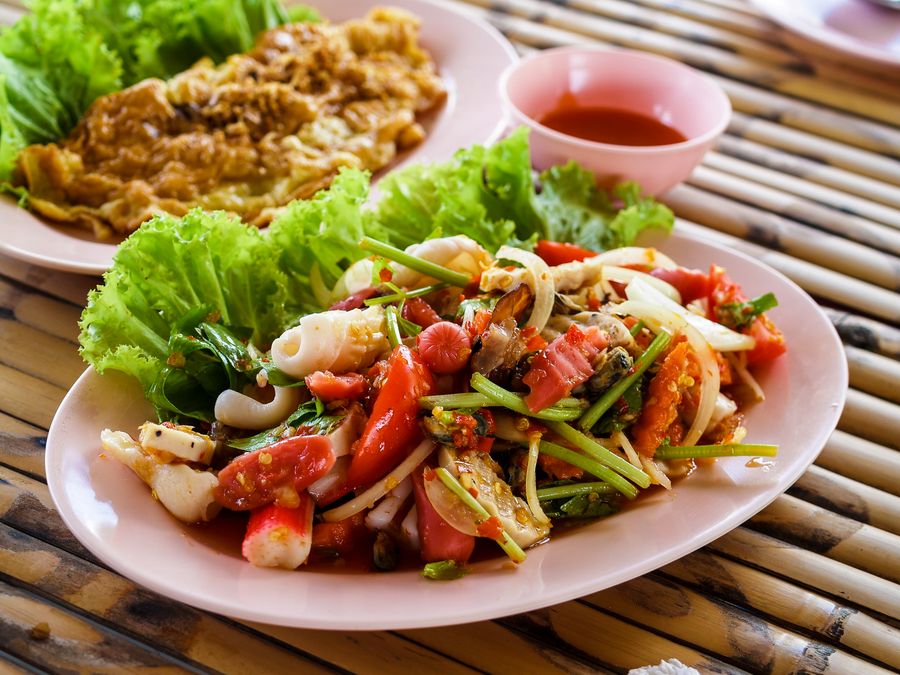 Thailändsk skaldjurssallad med bläckfisk, tomat och chili, serverad med omelett och sötstark sås.