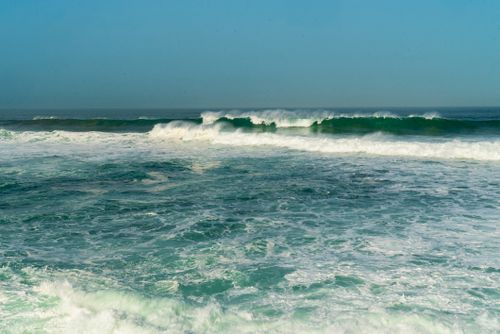 Free Breathtaking view of ocean waves in motion under a vibrant blue sky, capturing nature's beauty. Stock Photo
