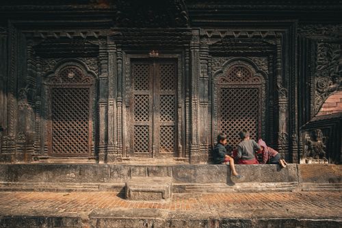 Free Children enjoy playing on the steps of a historic building with intricate wooden carvings. Stock Photo