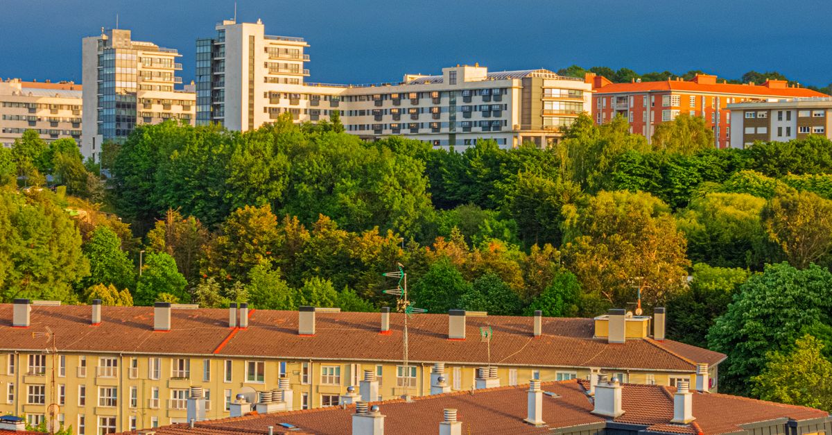 A scenic urban landscape featuring modern buildings and lush greenery at sunset.