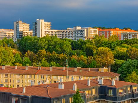 A scenic urban landscape featuring modern buildings and lush greenery at sunset.