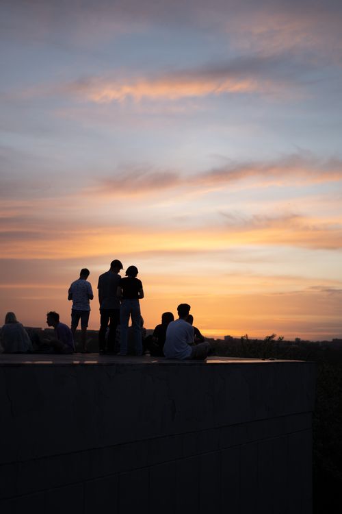 Free A group of people silhouetted against a beautiful sunset sky, creating a serene outdoor scene. Stock Photo