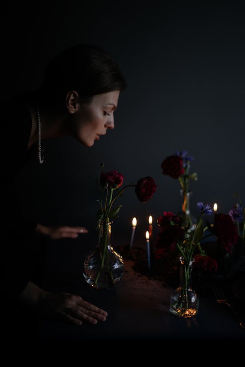 Woman by Table with Flowers in Candlelight