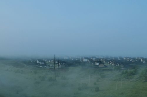 Free Aerial shot of rural houses shrouded in fog, creating a serene and mysterious atmosphere. Stock Photo