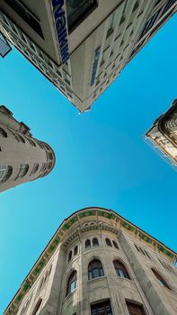 Dramatic low angle view capturing historic buildings against a clear blue sky.