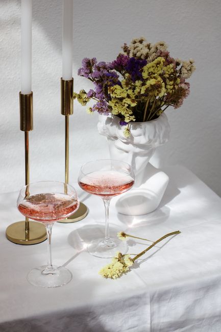 Stylish table arrangement with flowers, candles, and drinks for a chic setting.
