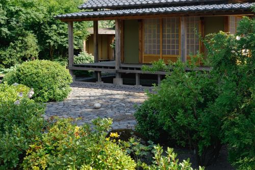 Free A traditional Japanese tea house surrounded by lush foliage, capturing serene ambiance and architectural elegance. Stock Photo