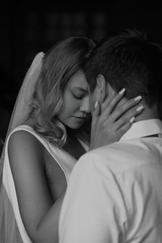 Intimate black and white portrait of a bride and groom sharing a tender moment.
