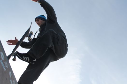 Skilled skateboarder performs an impressive stunt mid-air at an open skatepark on a clear day.. skilled, skateboarder, perfor