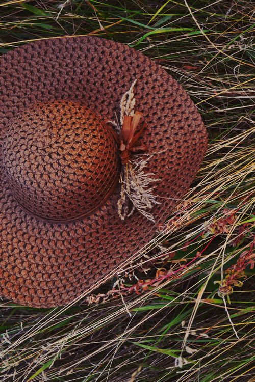 Free Closeup of a straw sun hat resting on dry grass, creating an earthy and rustic feel. Stock Photo