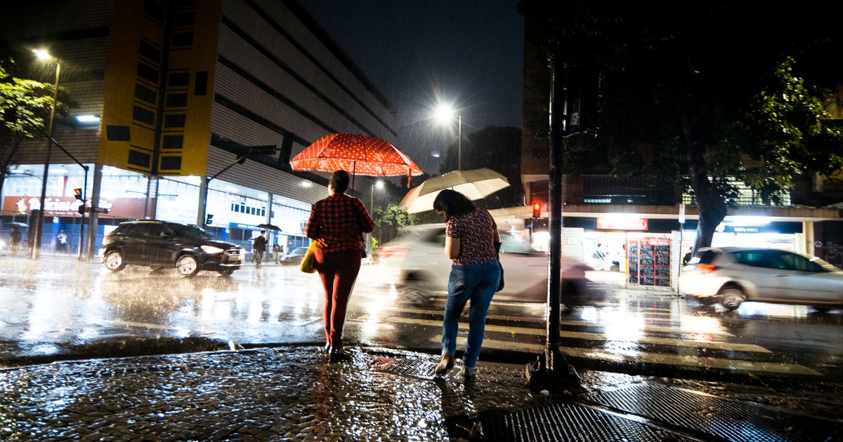 夜の大雨の中、傘をさして歩く人
