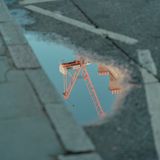 Crane reflected in a street puddle, photo by Zechen Li on Pexels