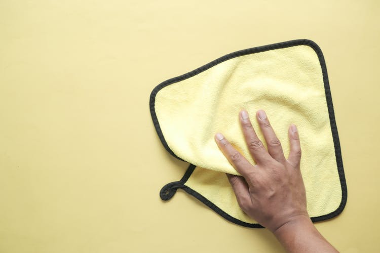 Hand Holding A Yellow Microfiber Towel