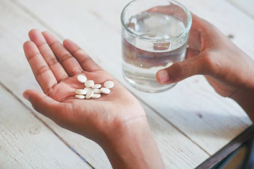 A Person with a Glass of Water Drinking Medicines