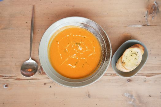 Delicious pumpkin soup served with garlic bread on a rustic wooden table, perfect for a cozy meal.