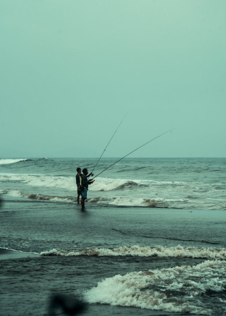 Men Fishing In The Wavy Ocean 