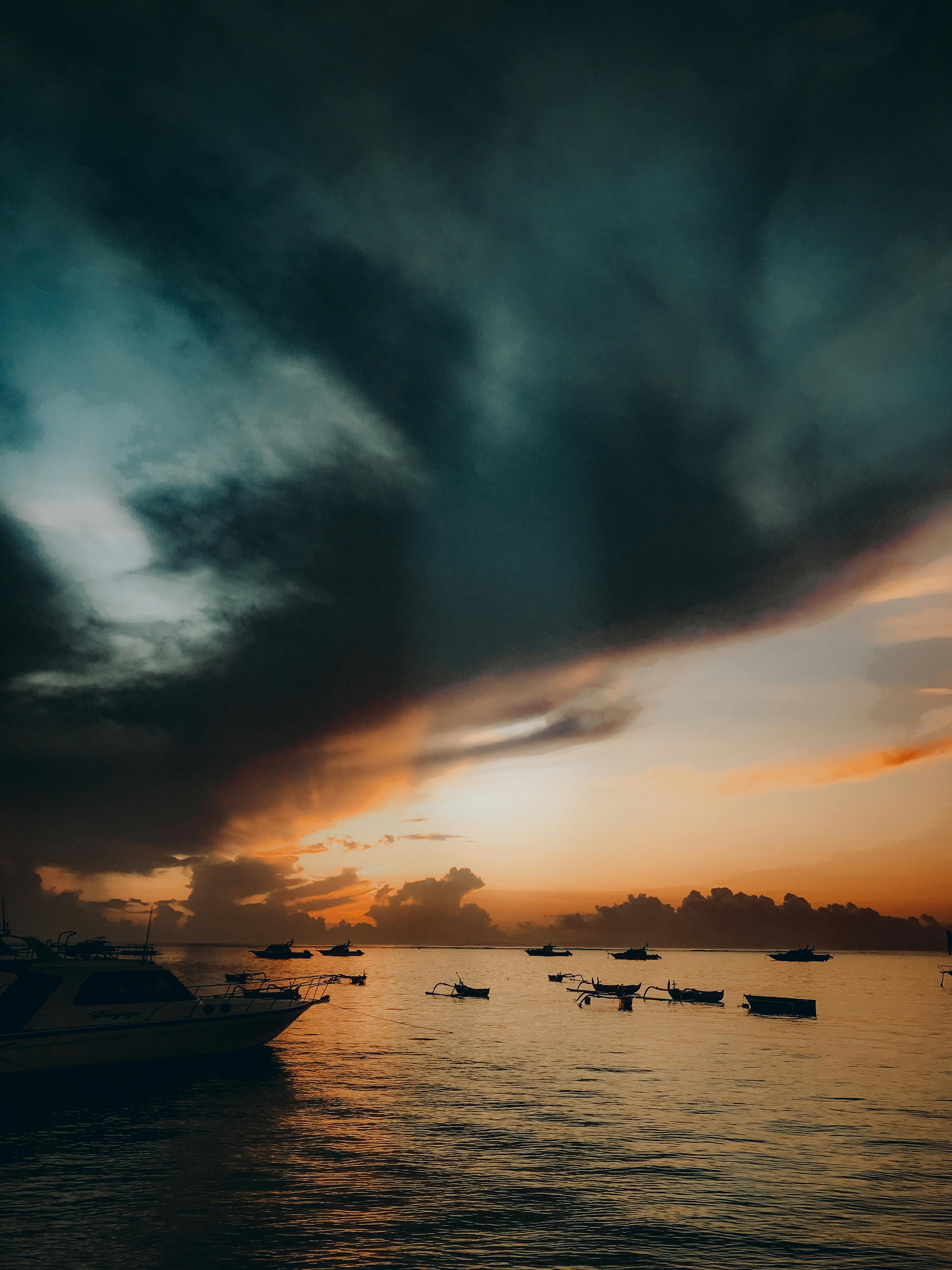 令人惊叹的日落，平静的海面上有船只，在戏剧性的天空下