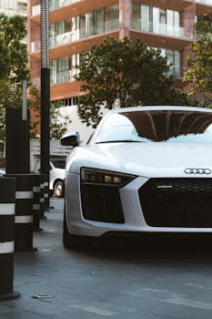 White Audi R8 luxury car parked on a contemporary urban street, showcasing sleek design and elegance.