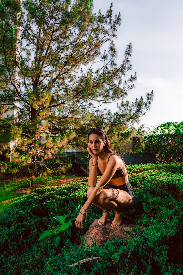 Woman Crouching On A Rock Outdoors