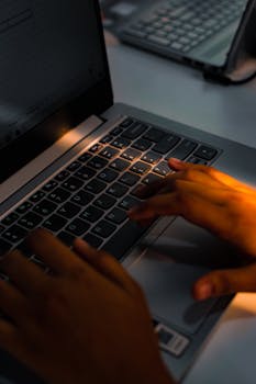 A close-up shot of hands typing on a laptop keyboard, highlighting office work.