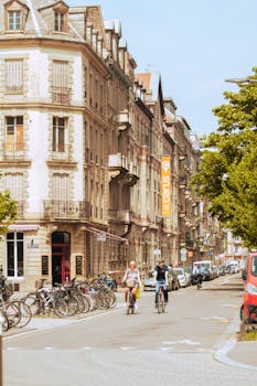 Street view of cyclists enjoying a summer day in Strasbourg, France, showcasing historic architecture.